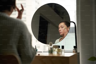 여자가 거울에 비친 자신의 모습을 보고 있다