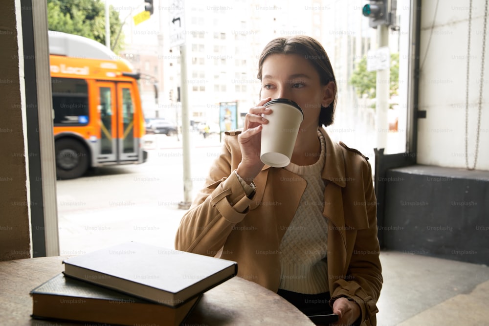 a woman sitting at a table drinking from a coffee cup