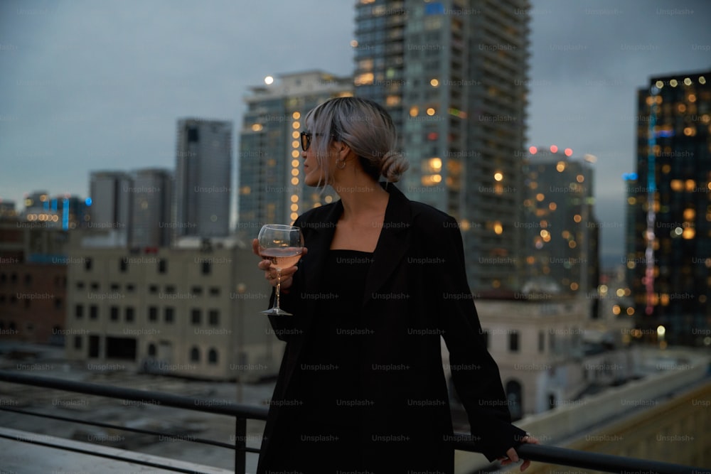 Eine Frau steht auf einem Balkon und hält ein Glas Wein in der Hand
