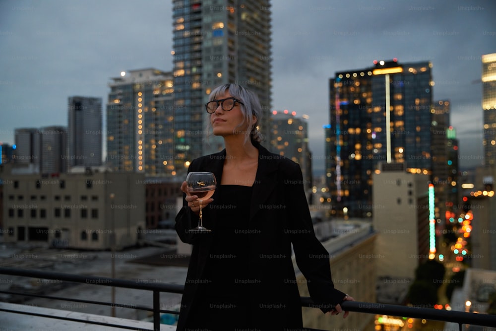 Une femme debout sur un balcon tenant un verre de vin