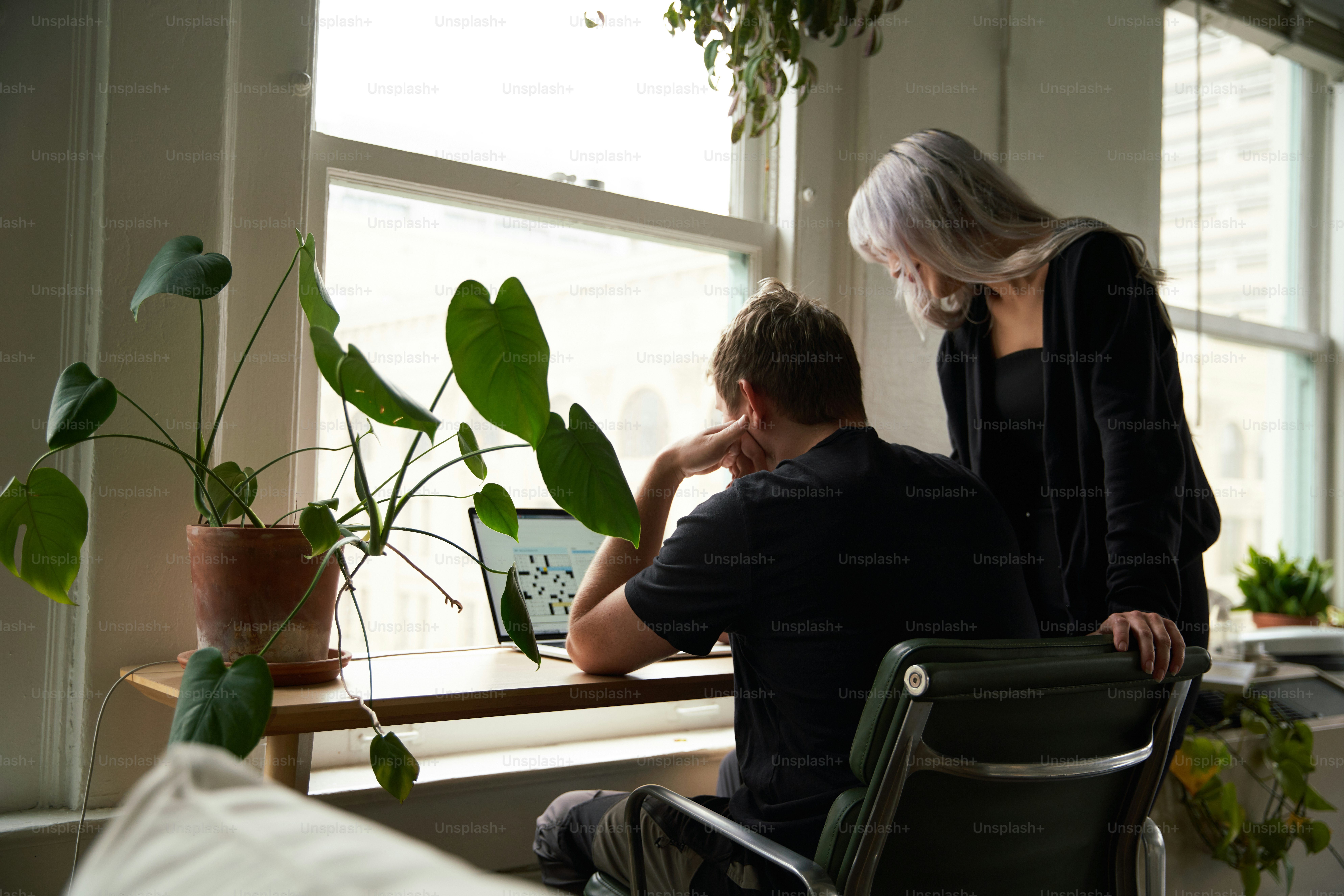 a man and a woman sitting at a table looking at a laptop