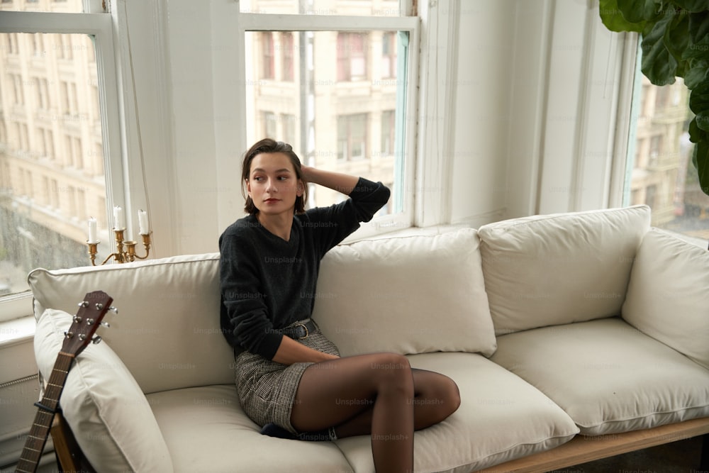 Una donna seduta sopra un divano accanto a una finestra