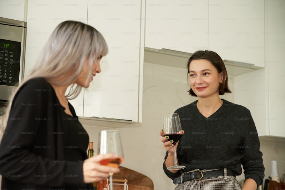 a couple of women standing next to each other holding wine glasses