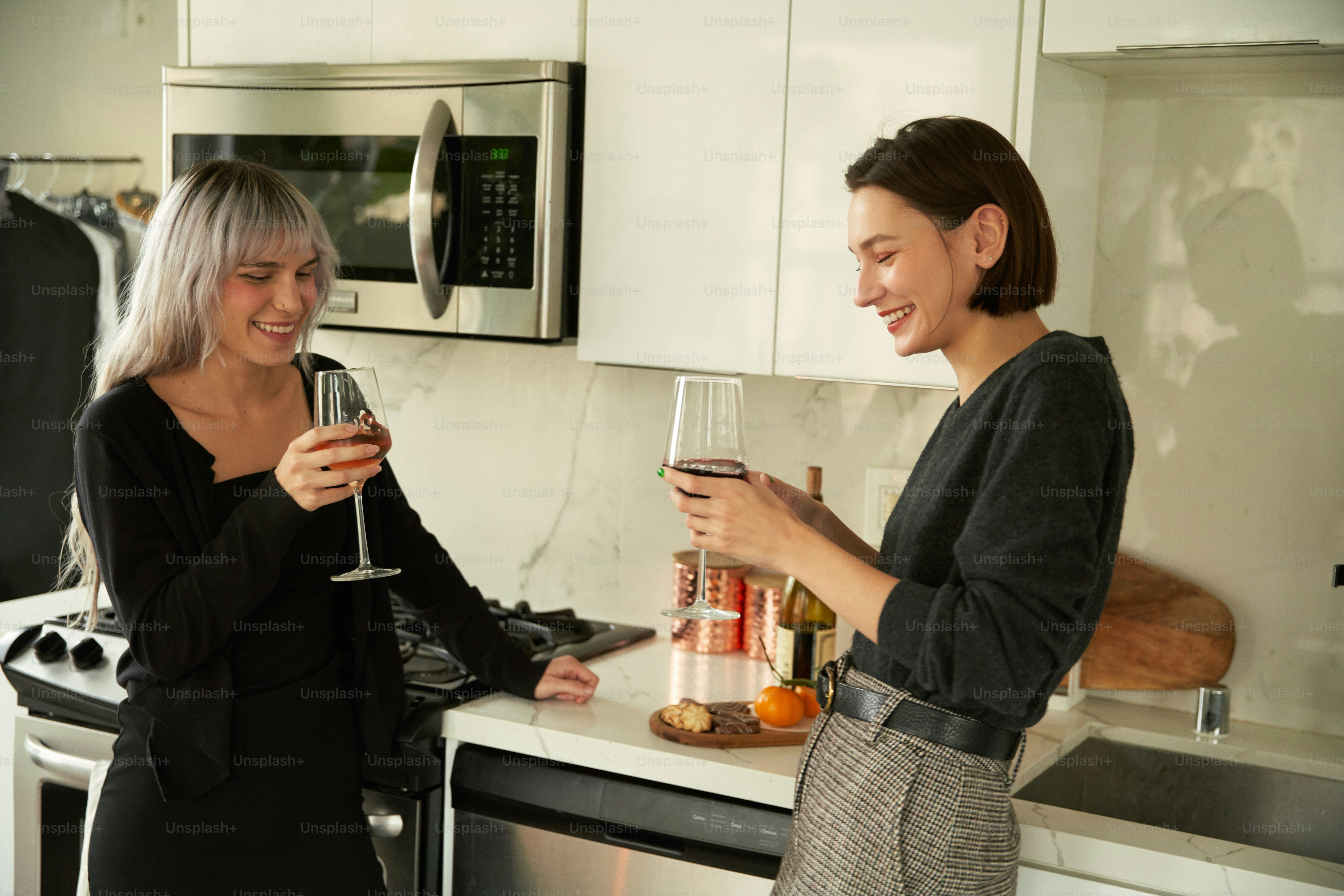 a couple of women standing next to each other holding wine glasses