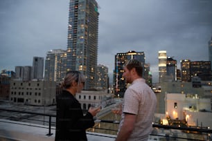 um homem e uma mulher em pé em uma varanda com vista para uma cidade