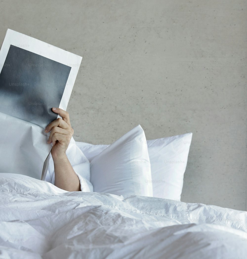 une personne allongée dans son lit en train de lire un livre
