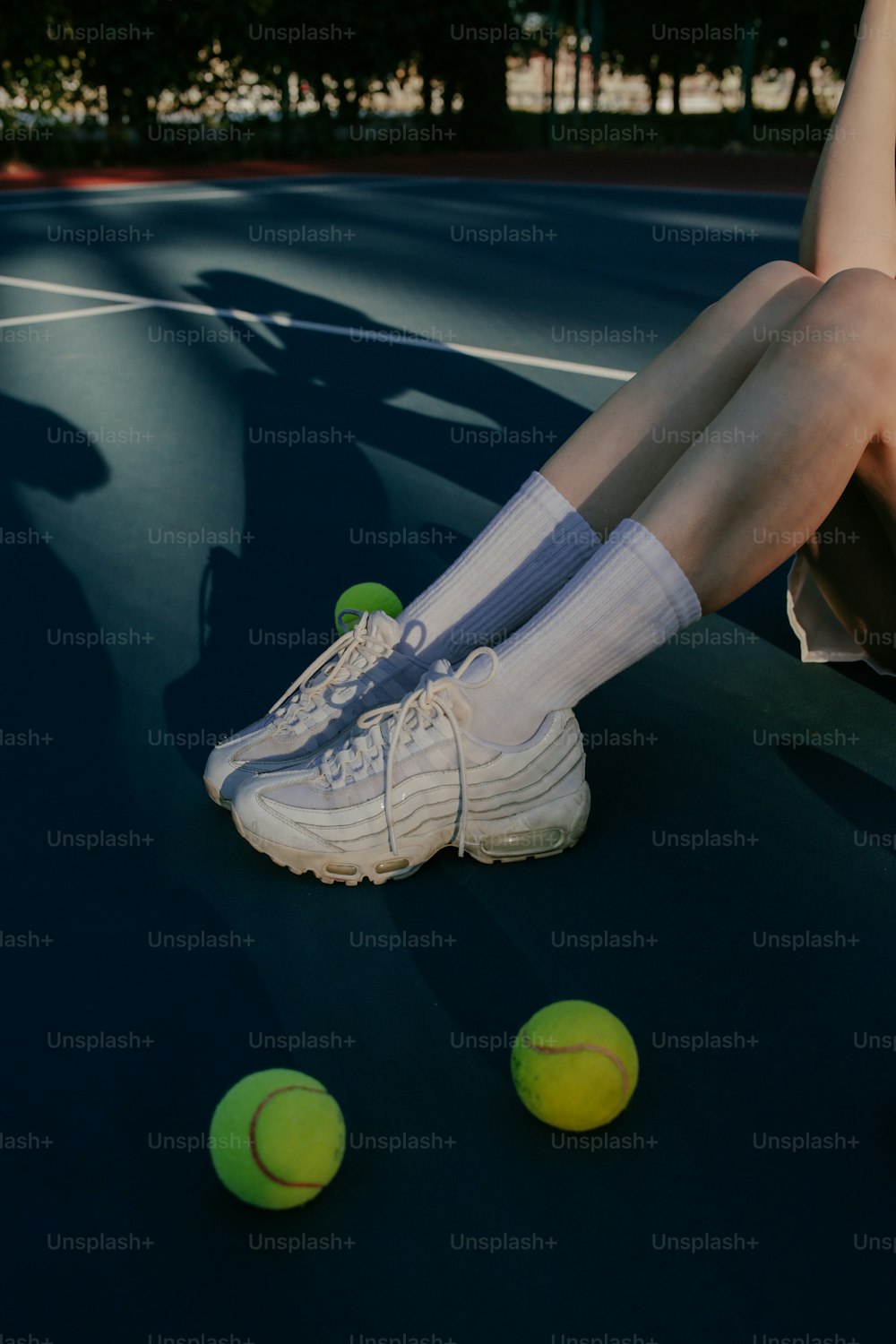 eine Person, die mit Tennisbällen auf einem Tennisplatz sitzt