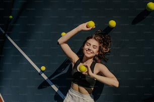 uma mulher segurando duas bolas de tênis e uma raquete de tênis