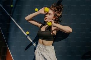 두 개의 테니스 공과 테니스 라켓을 들고 있는 여자