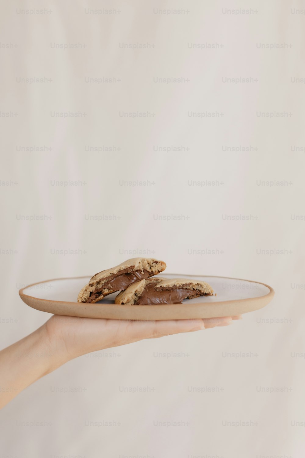 a person holding a plate with a cookie on it