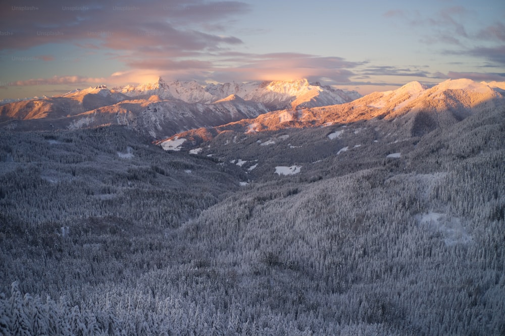 uma vista de uma cordilheira nevada ao pôr do sol