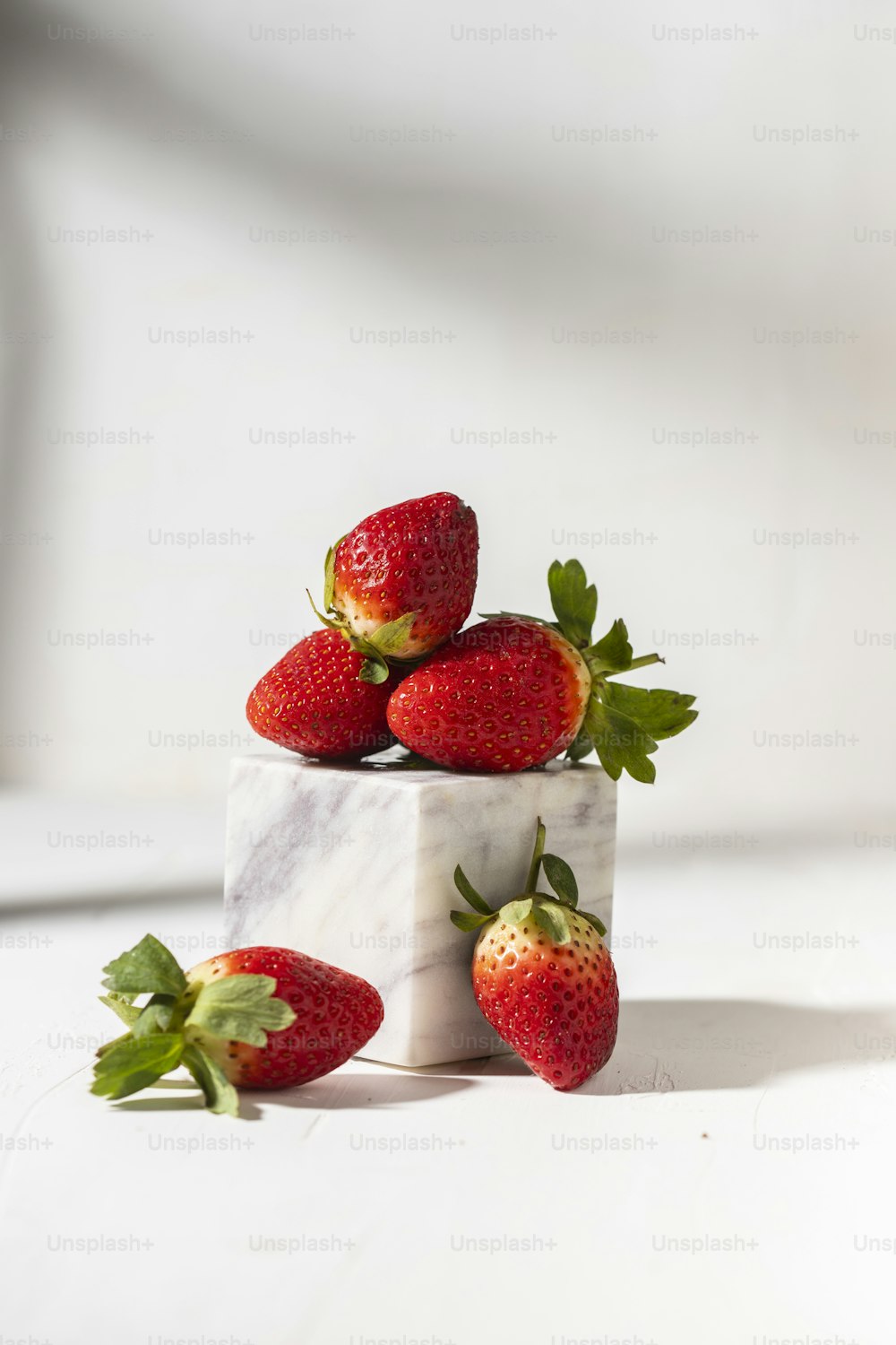 four strawberries sitting on top of a marble block