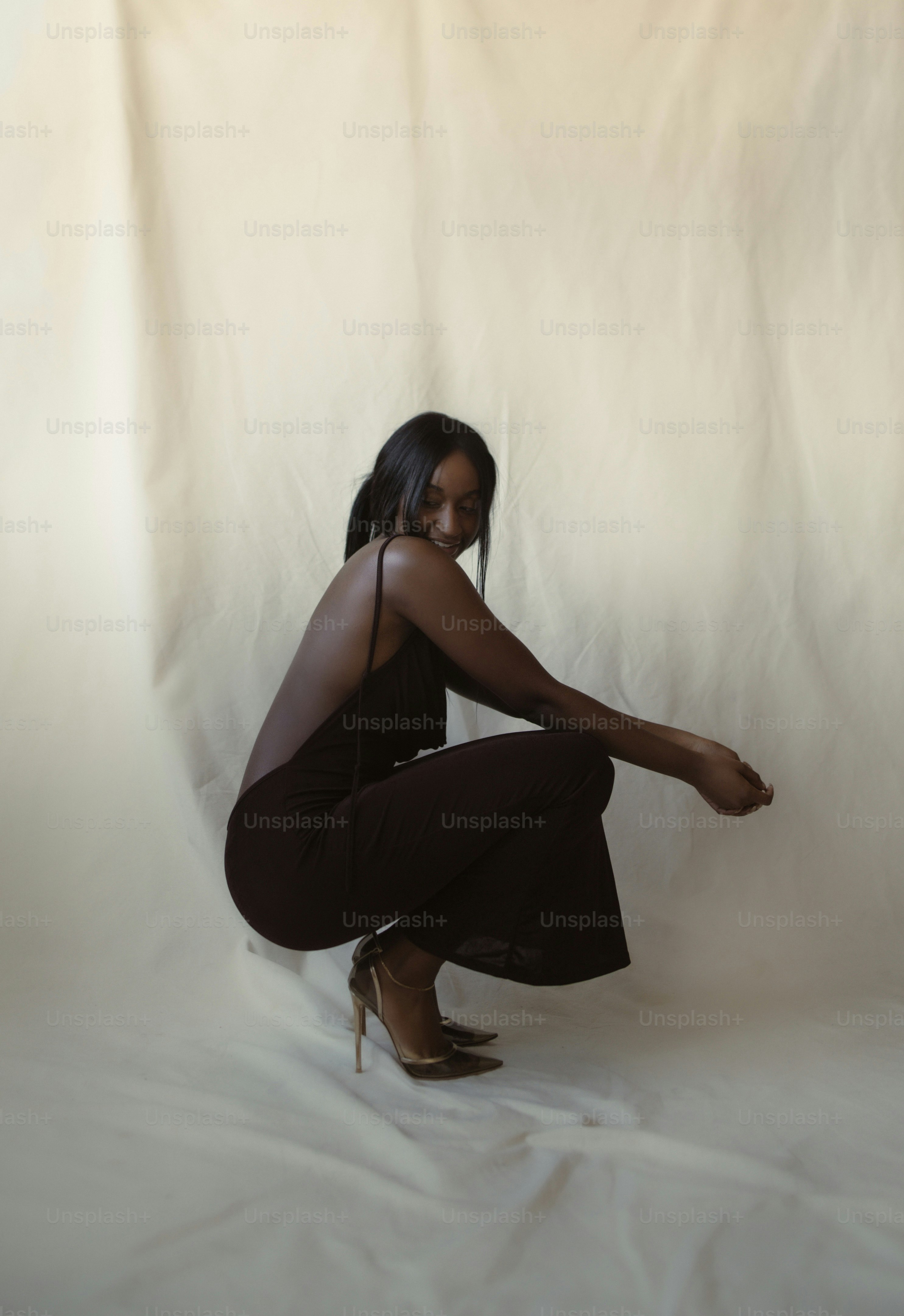a woman kneeling on a white background posing for a picture