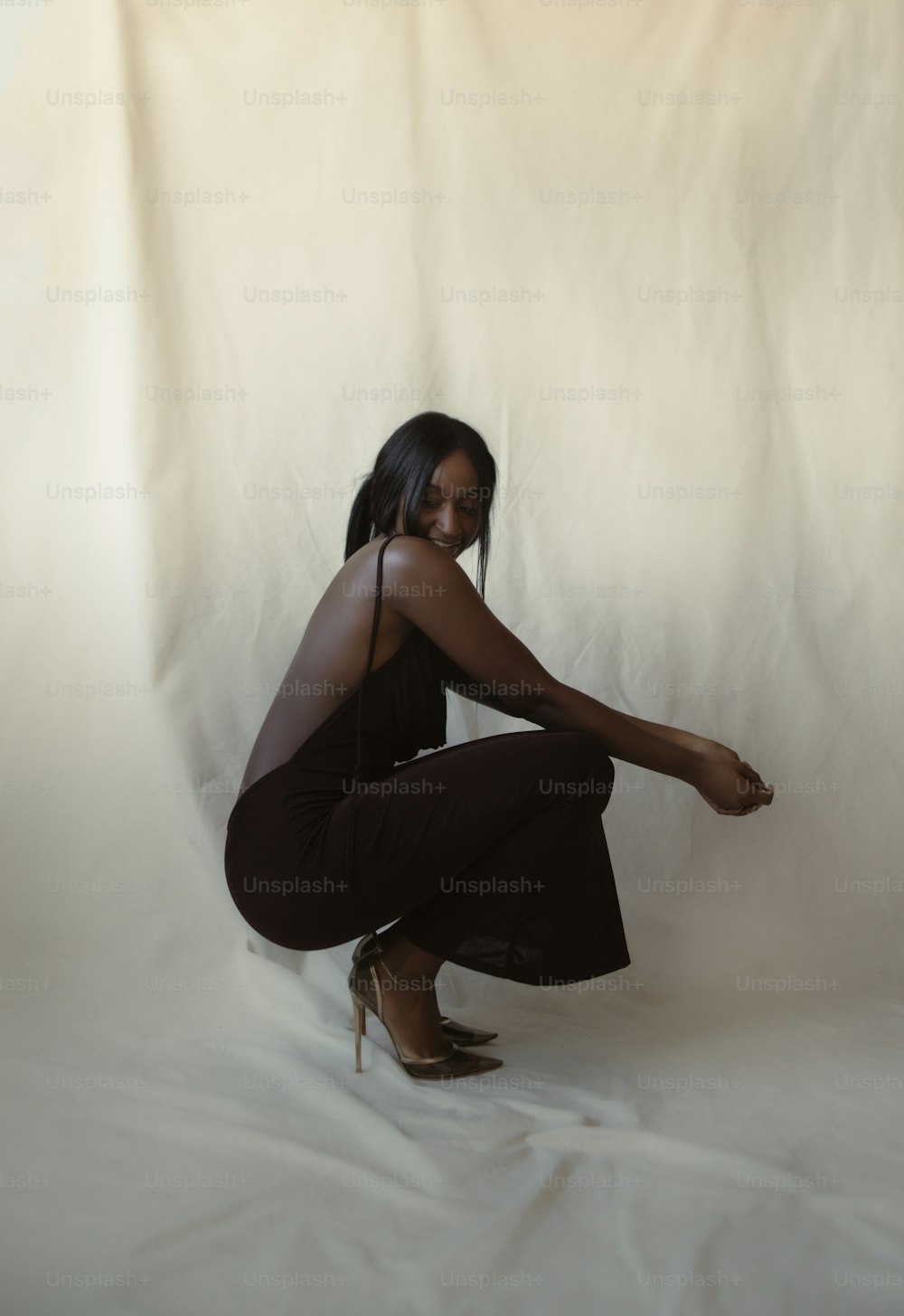 a woman kneeling on a white background posing for a picture