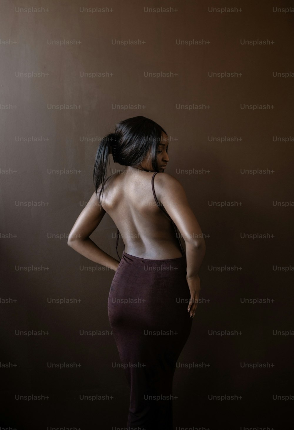 Una donna in piedi in una stanza buia con le spalle alla telecamera