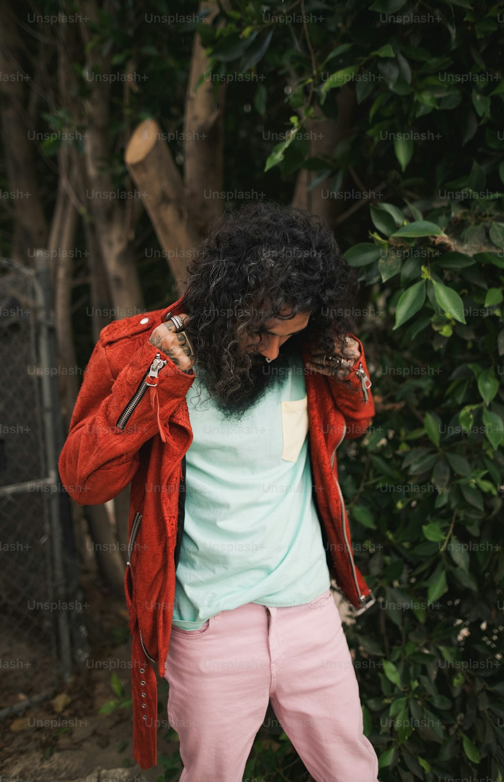 a man with long hair wearing pink pants and a red jacket