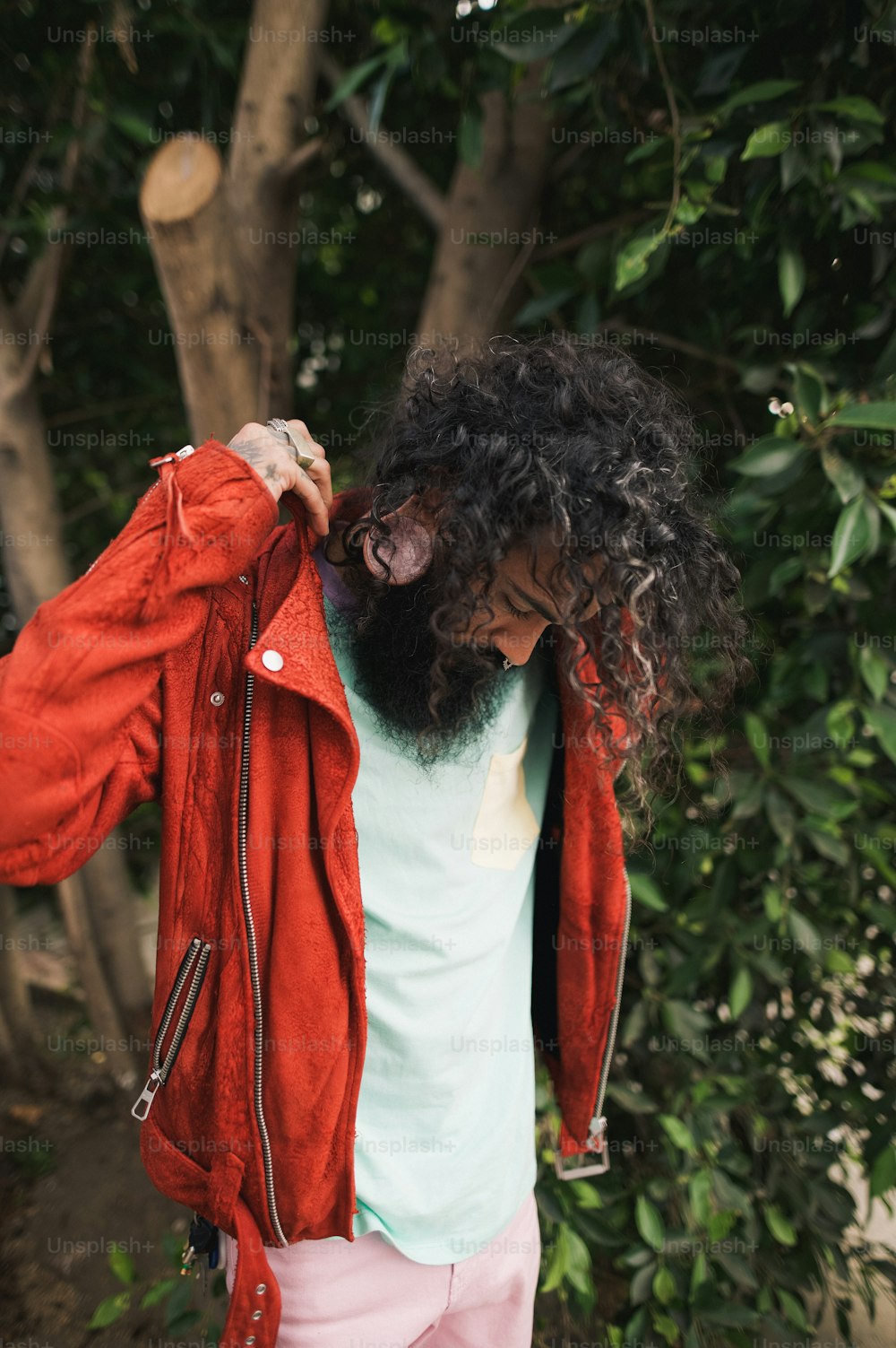 a man with long hair and a beard wearing a red jacket