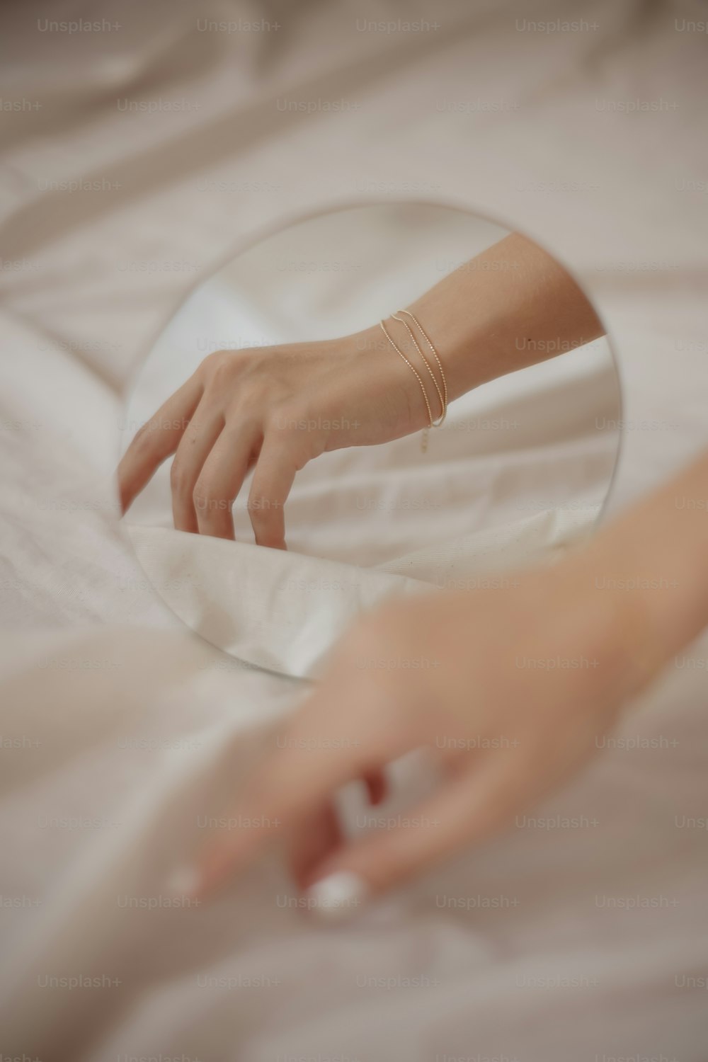 a person's hand touching a mirror on a bed
