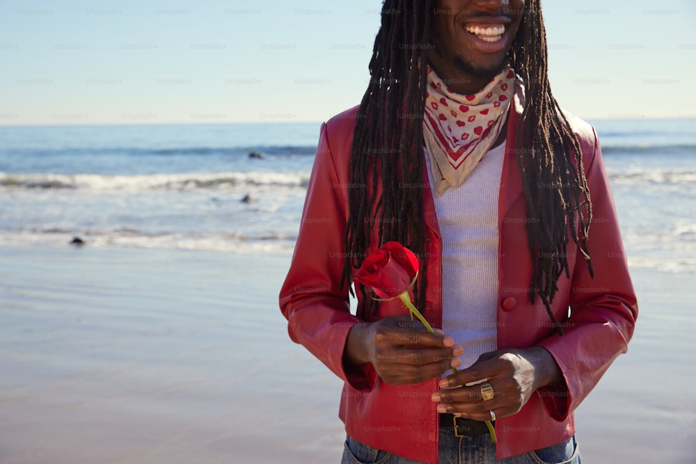 a man with dreadlocks standing on the beach