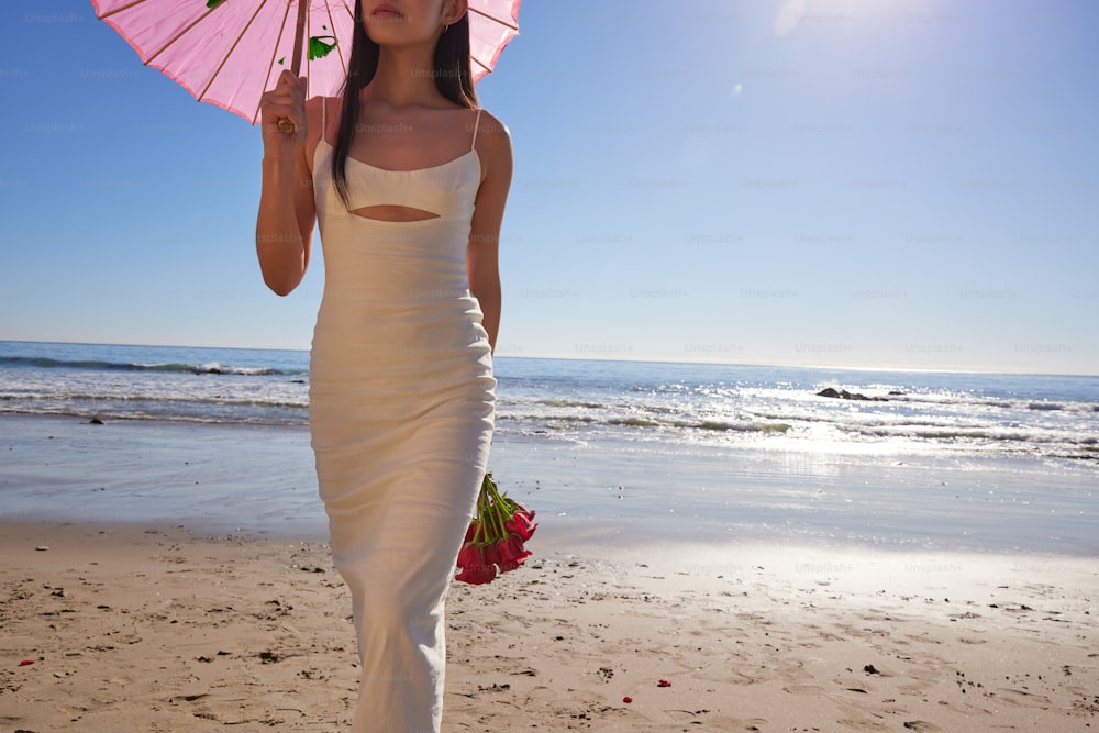 a woman in a white dress holding a pink umbrella