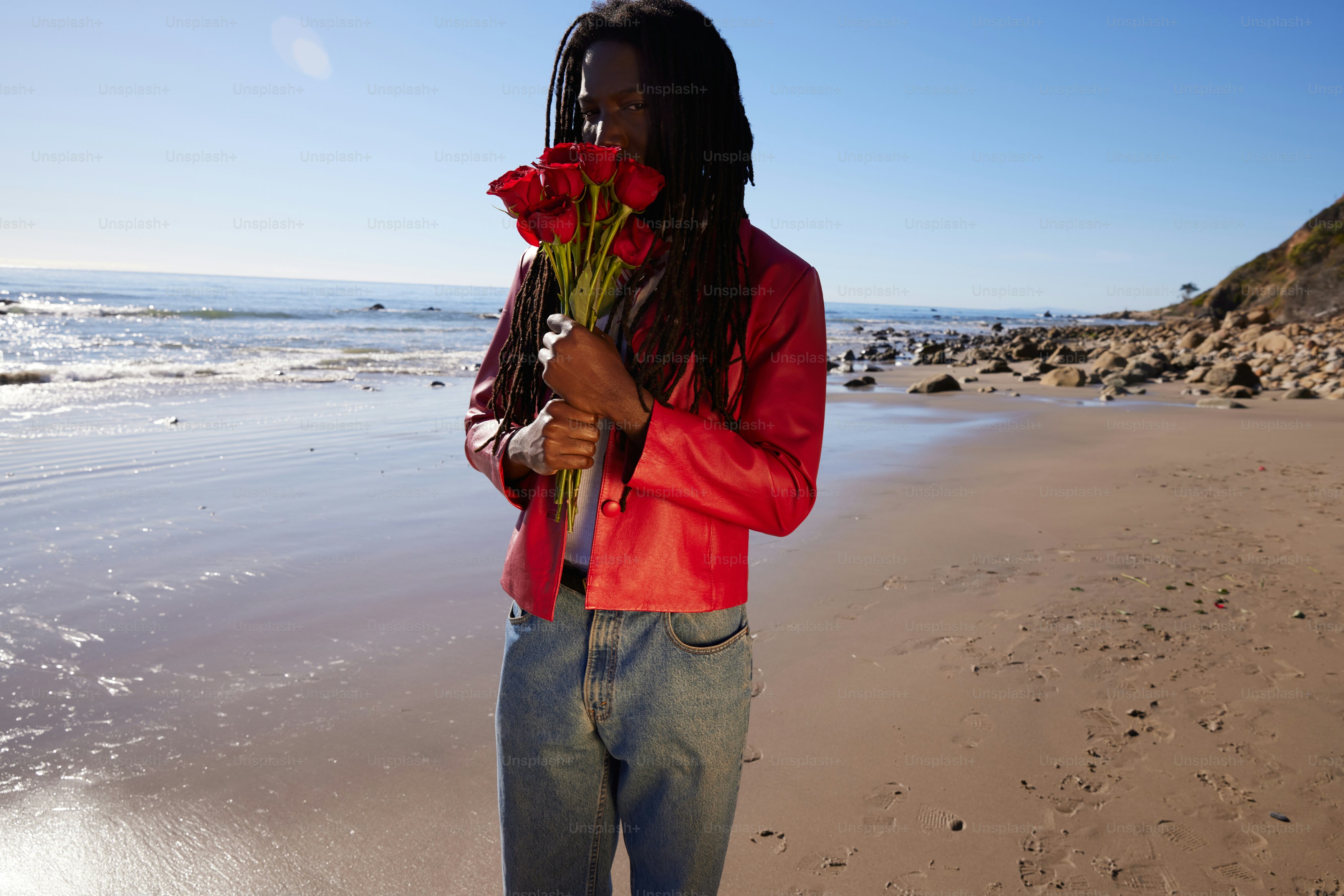a person standing on a beach with a flower in their hand