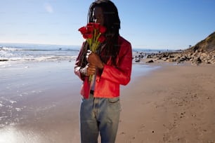 a person standing on a beach with a flower in their hand