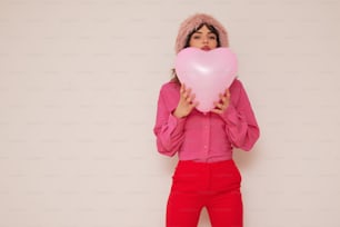 a woman in a pink shirt holding a heart shaped balloon