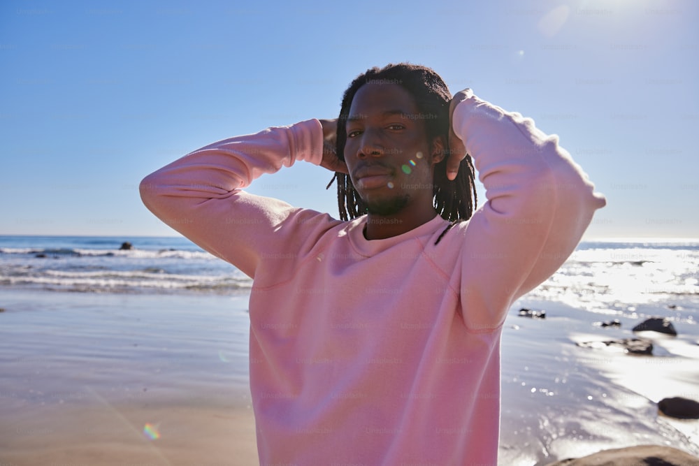 a man with dreadlocks standing on the beach