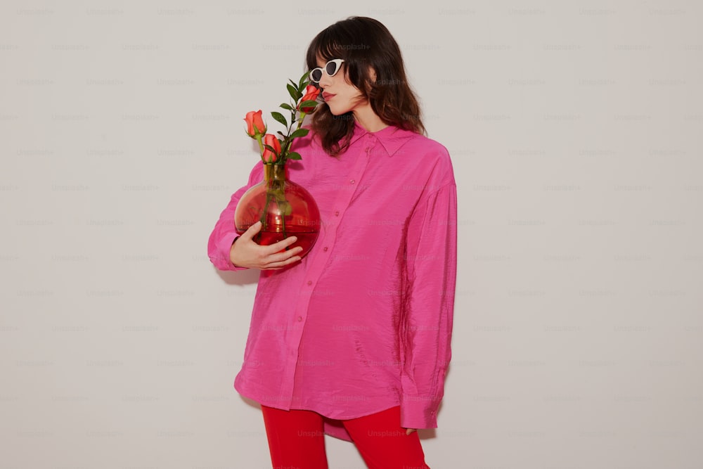 Una donna in una camicia rosa che tiene un vaso di fiori