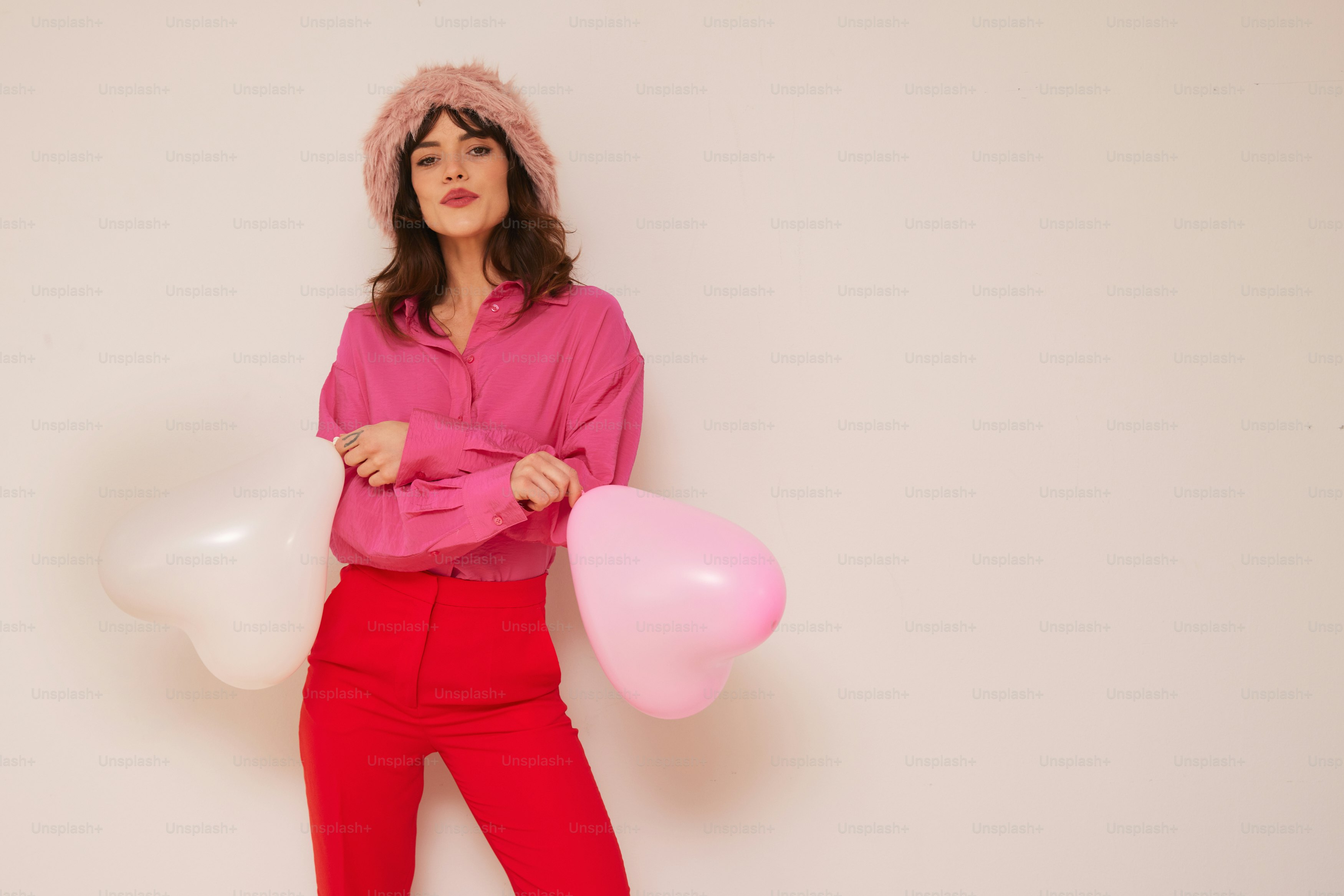 a woman in a pink shirt and red pants holding balloons