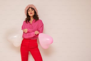 a woman in a pink shirt and red pants holding balloons