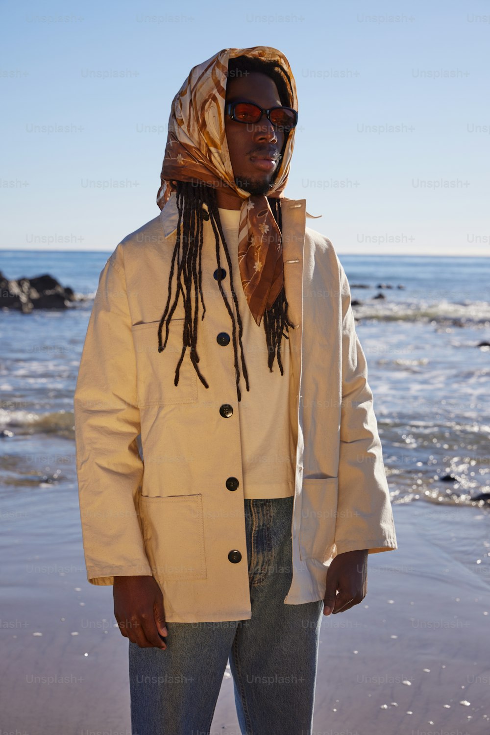 a man with dreadlocks standing on the beach