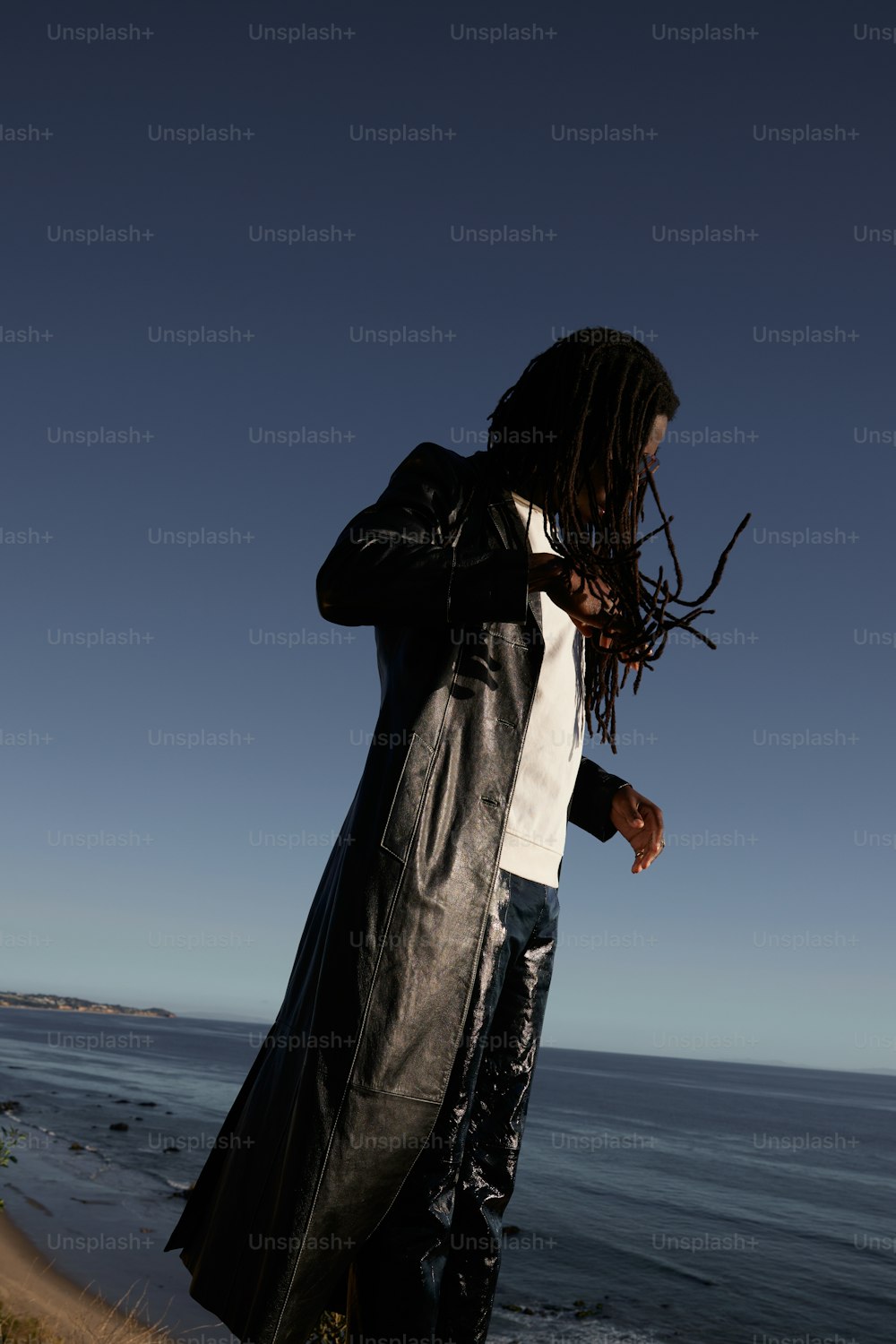 a man with dreadlocks standing by the ocean