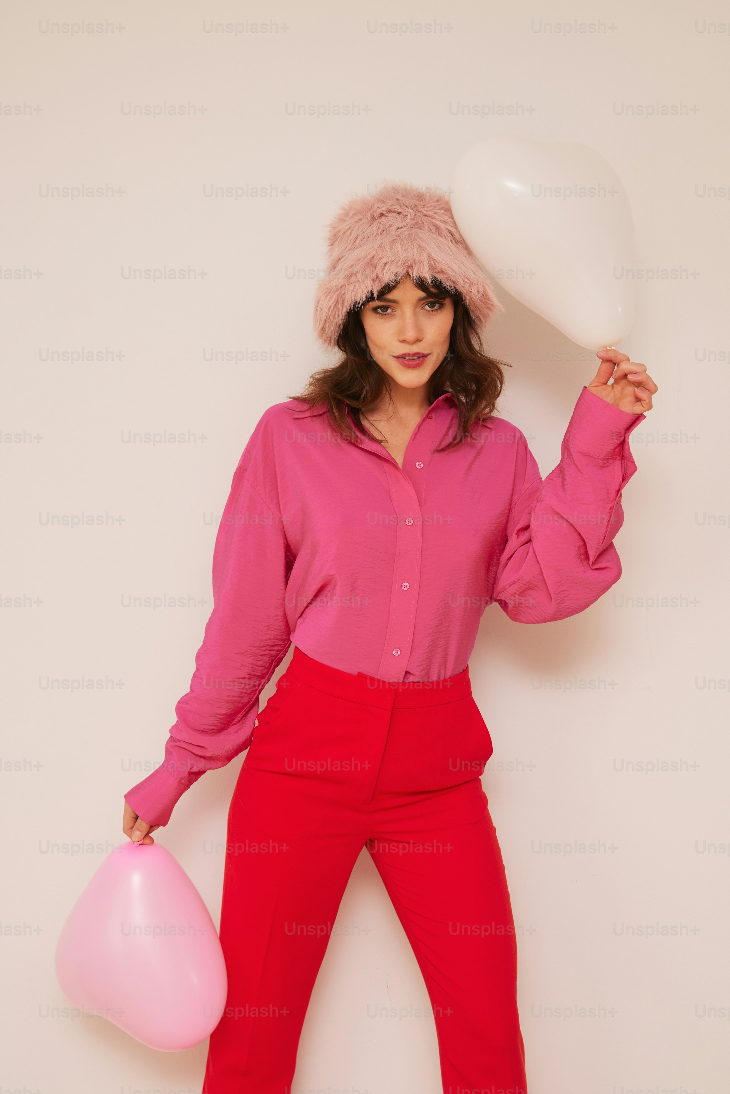 a woman in a pink shirt and red pants holding a balloon