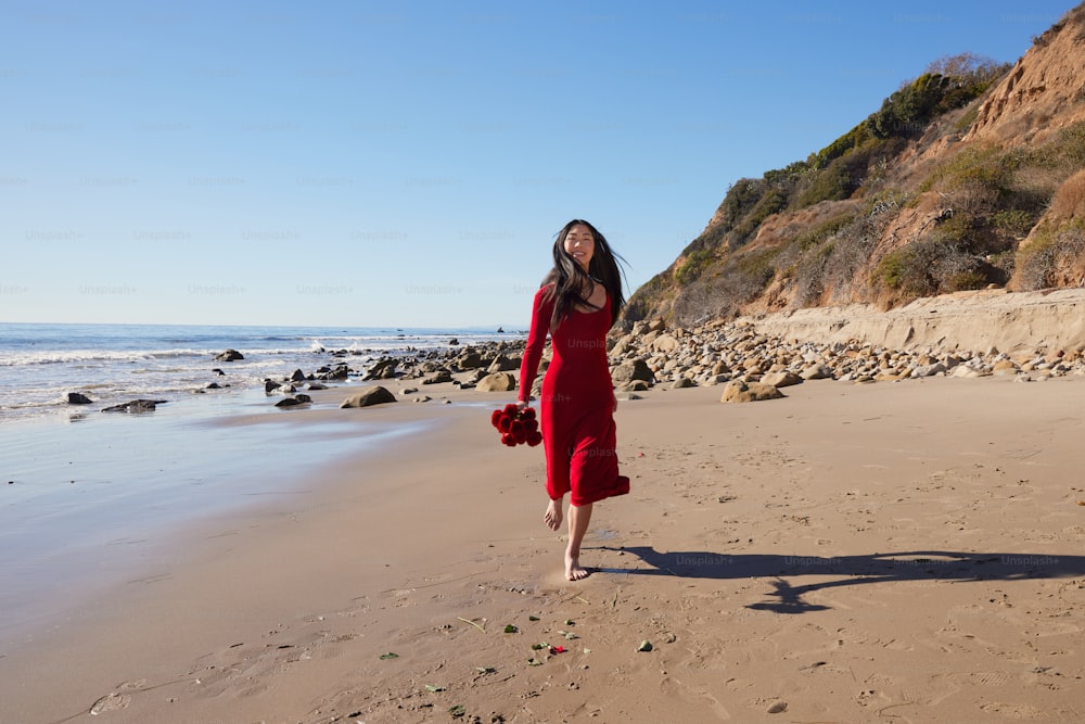 a woman in a red dress on a beach