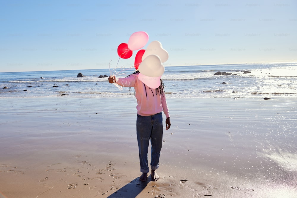 una persona su una spiaggia con un mucchio di palloncini