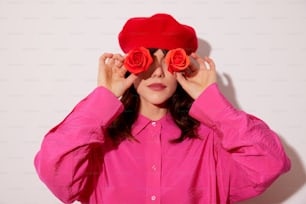 Une femme vêtue d’une chemise rose et d’un chapeau rose rouge couvrant ses yeux