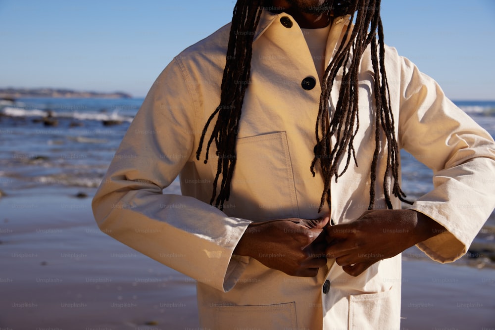 a man with dreadlocks standing on the beach