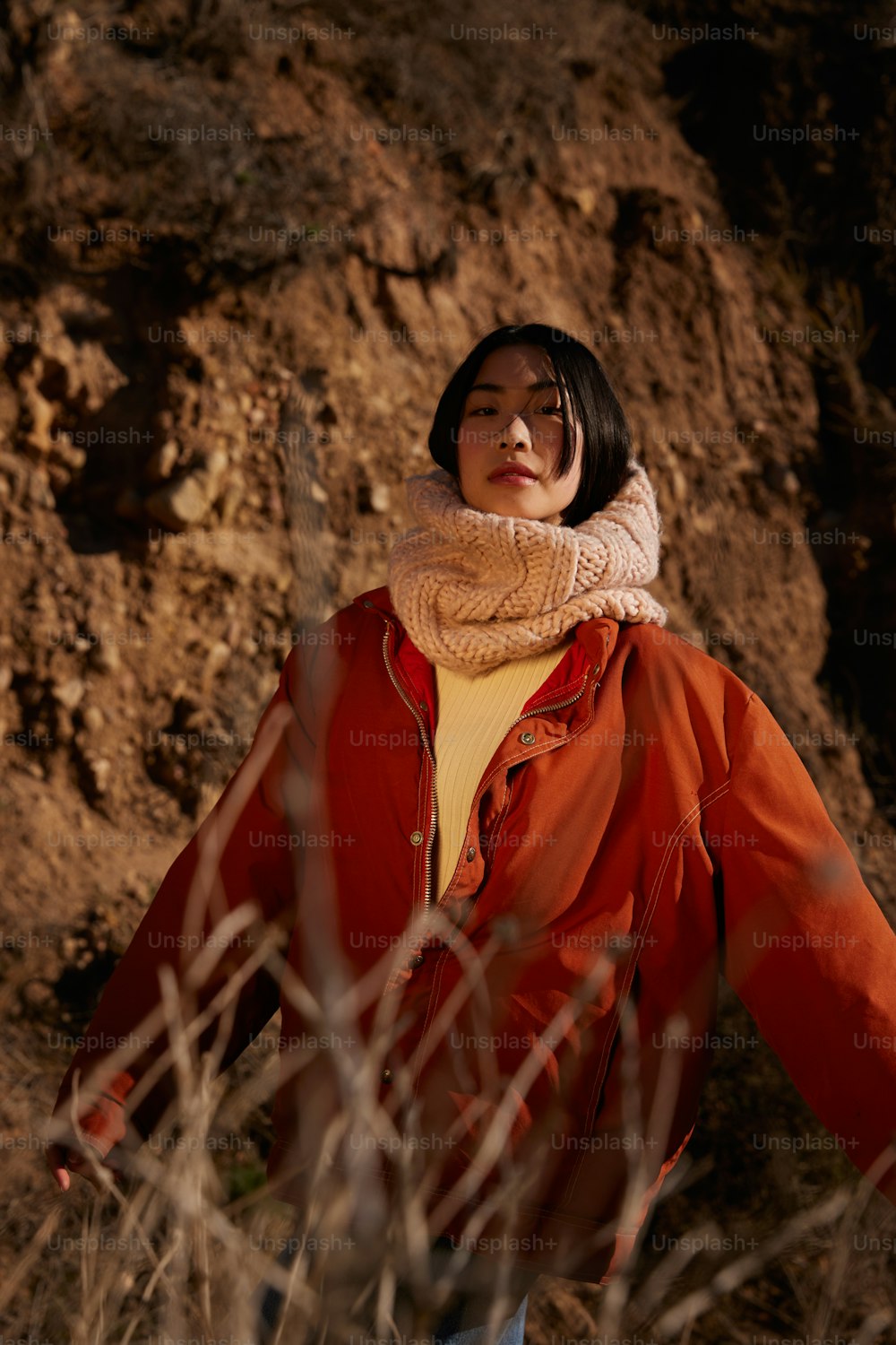 a woman standing in front of a large rock