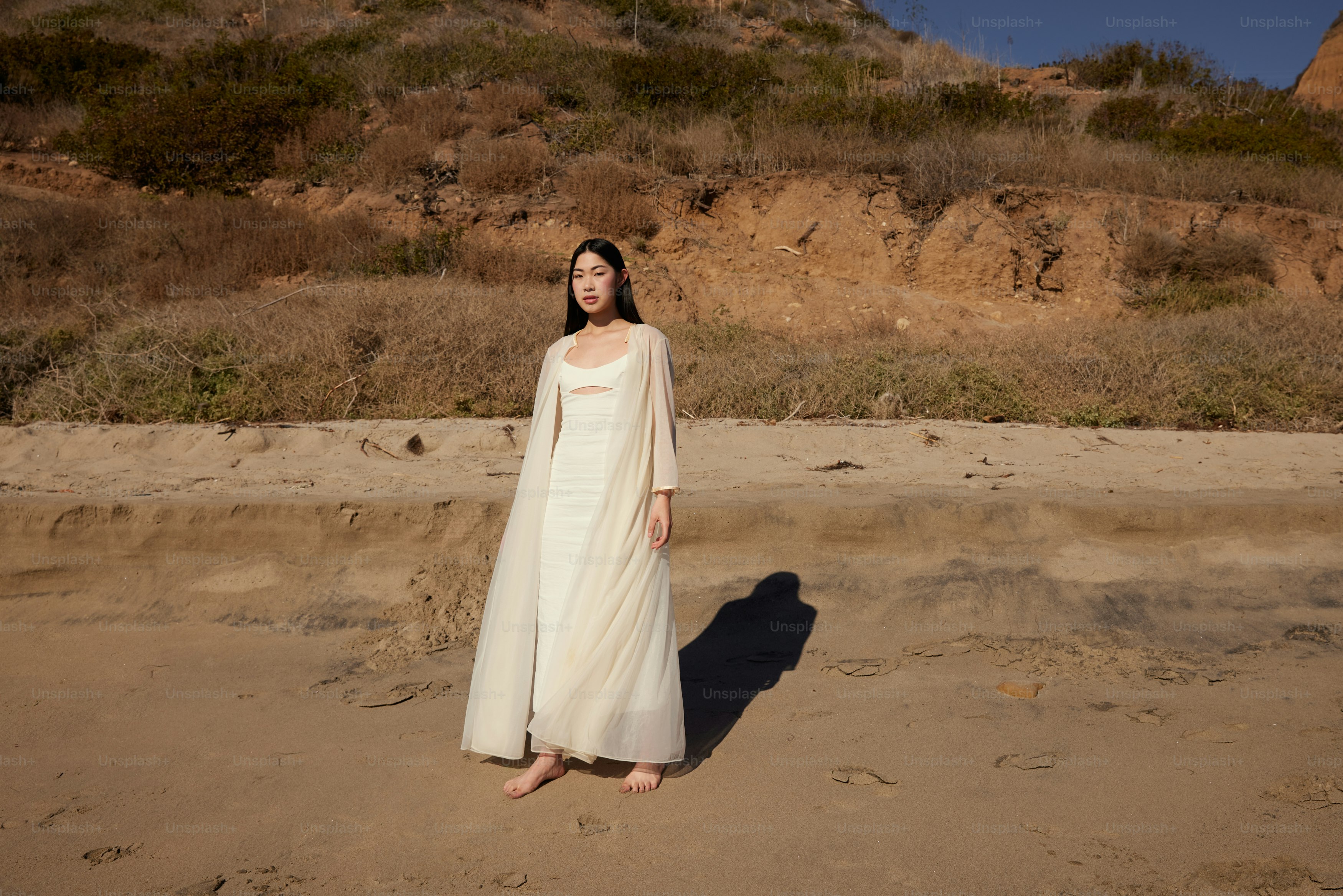 Eine Frau im weißen Kleid steht am Strand