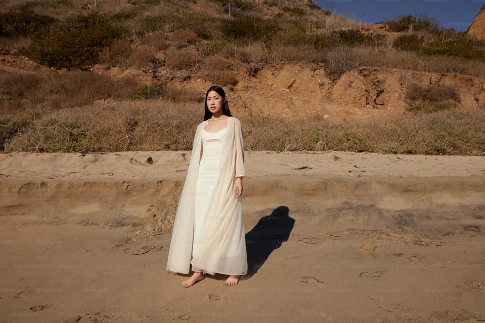 Una donna in un vestito bianco in piedi su una spiaggia