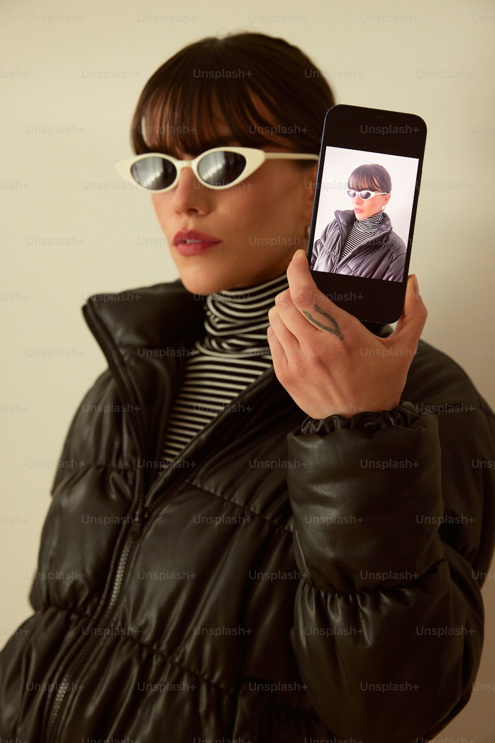 a woman wearing sunglasses holding up a cell phone
