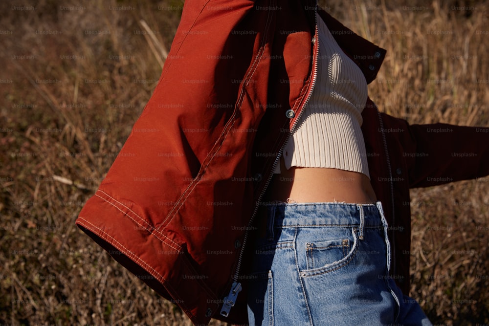 a woman wearing a red jacket and jeans