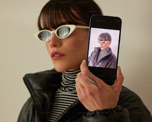a woman holding up a cell phone with a picture on it