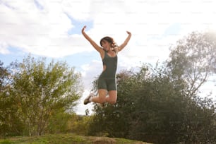 a woman jumping in the air with her arms outstretched