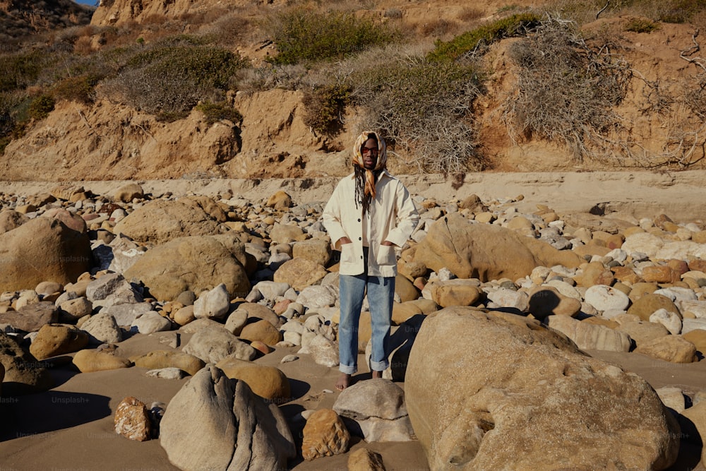 a woman standing on a rocky beach next to large rocks