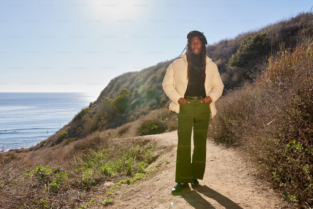 a man standing on a dirt road next to the ocean