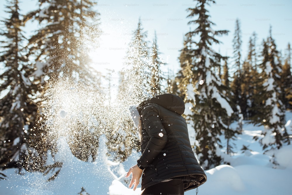 una persona in piedi nella neve di fronte ad alcuni alberi