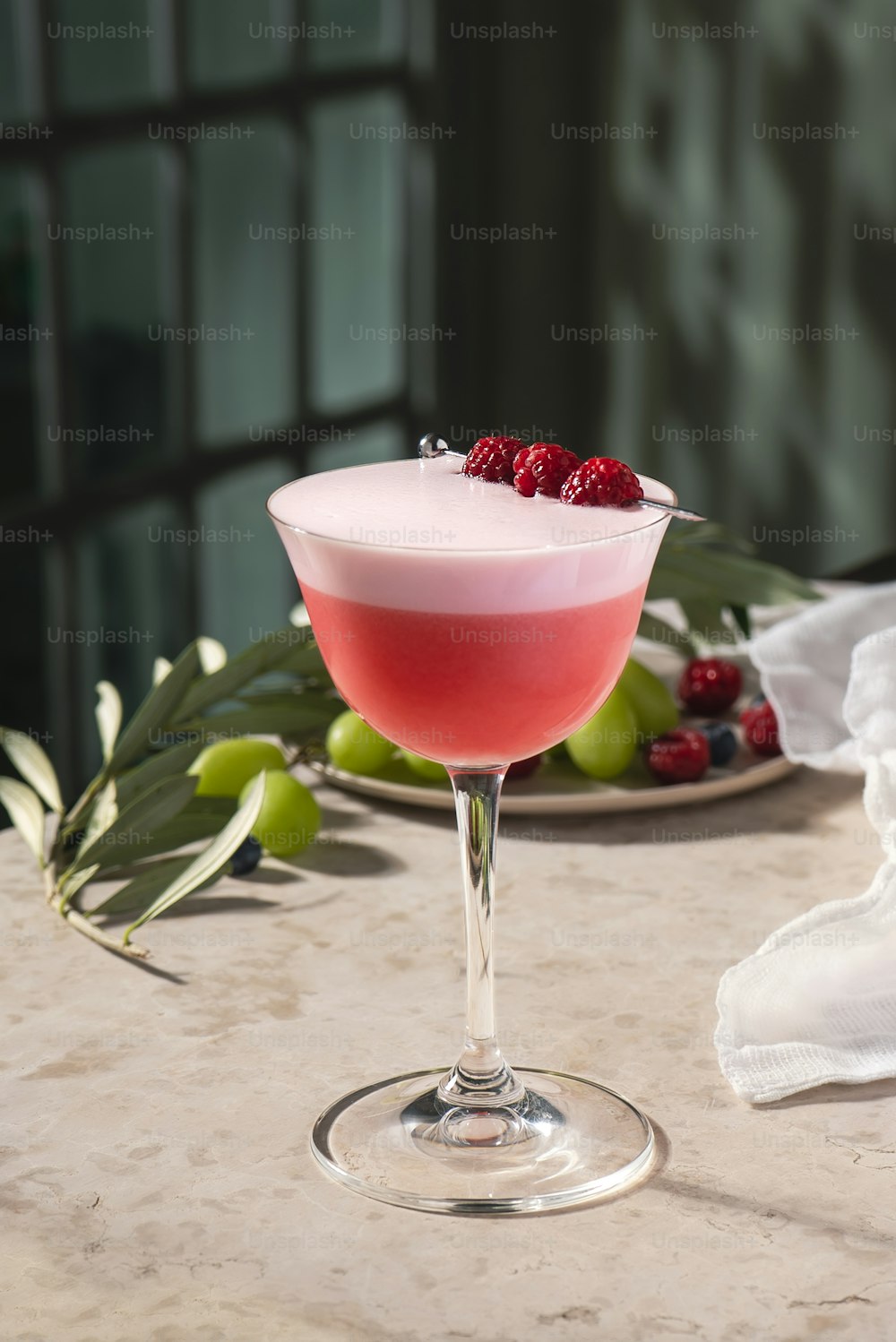 uma bebida rosa em um copo de vinho em uma mesa