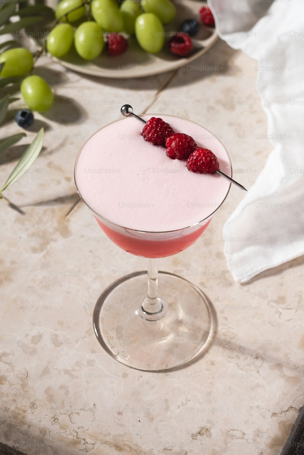 a pink drink with raspberries on the rim
